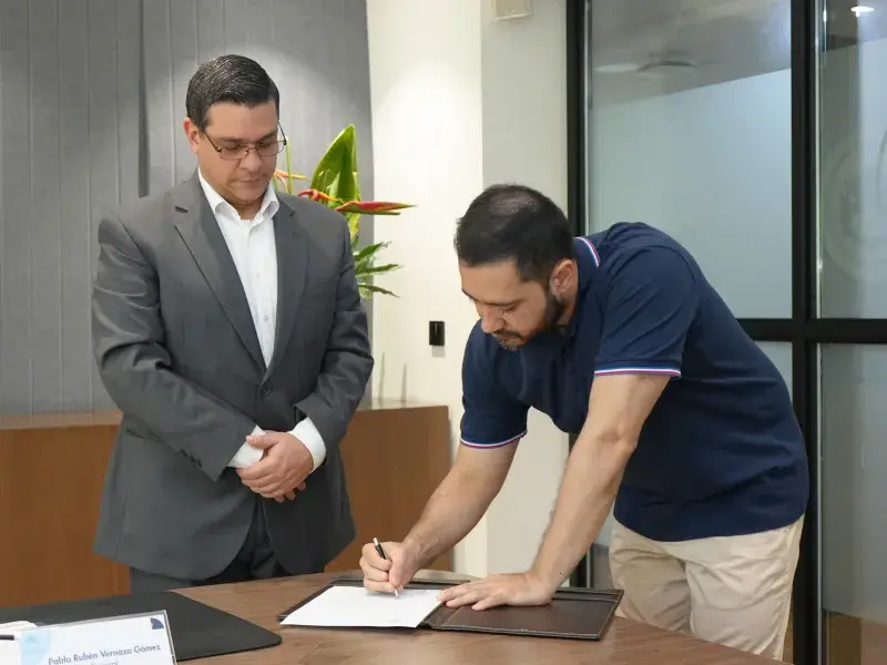 Carlos Andrés Castro Galvis, director de la Especialización en Medicina de Urgencias realizando la firma del acta de su posesión, a su izquierda Pablo Rubén Vernaza Gómez, secretario general de la Seccional. 